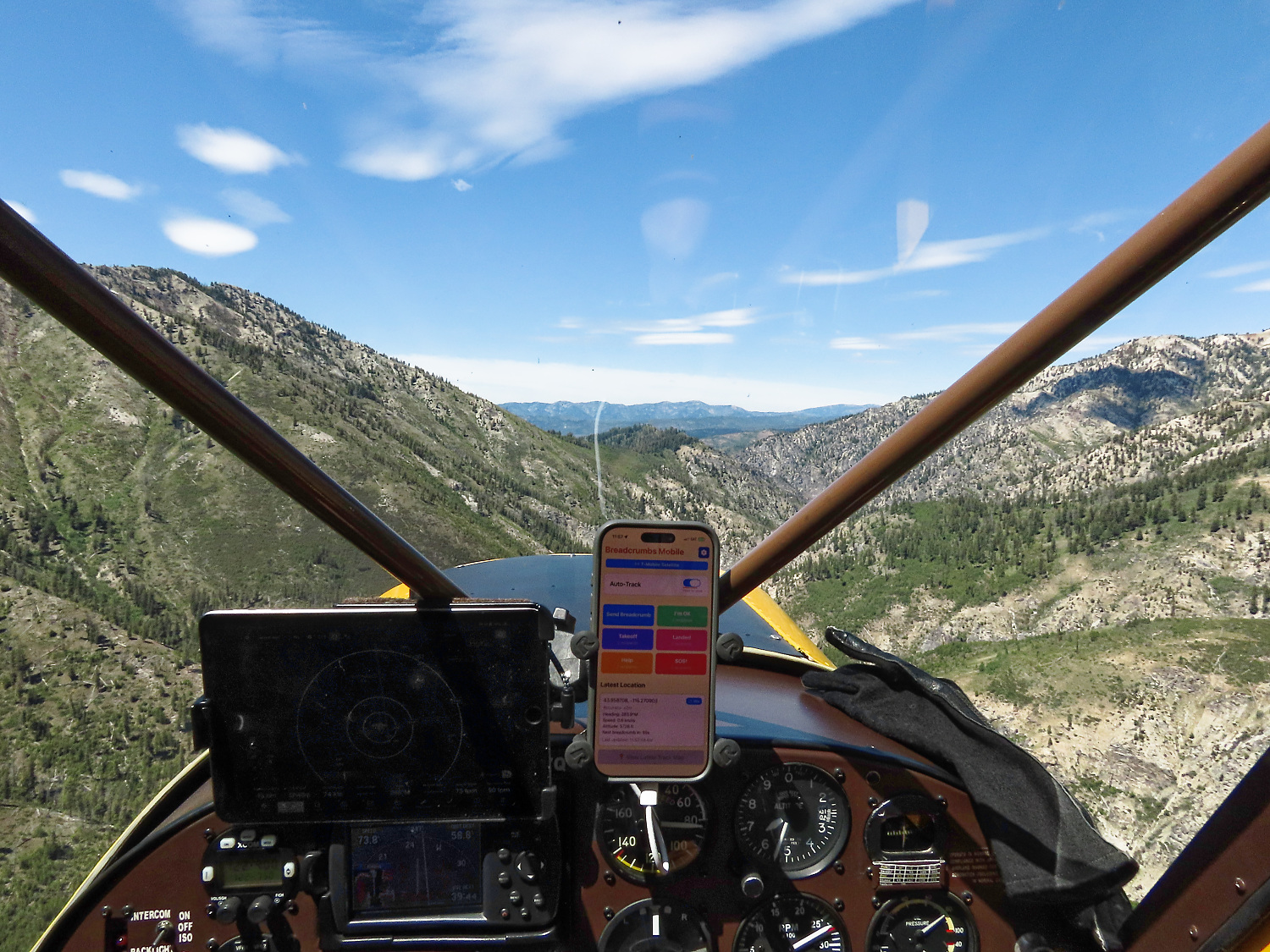 Breadcrumbs Mobile running on an iPhone mounted in a backcountry aircraft cockpit, snowy mountains ahead
